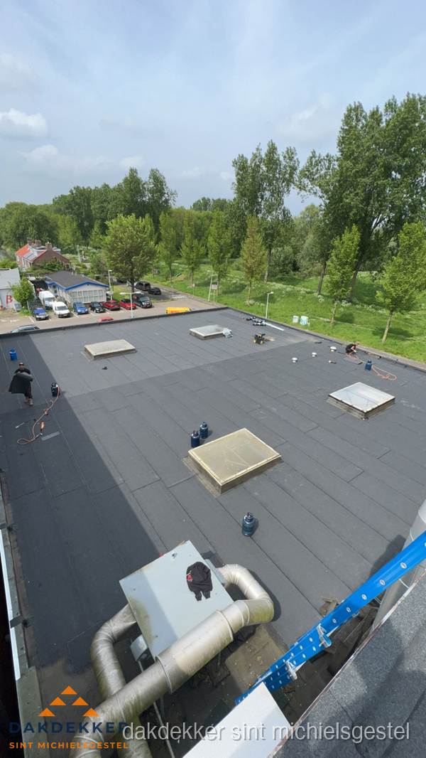 Dakdekker aan het werk op groot plat dak met bitumen in Sint Michielsgestel Dakdekker aan het werk op groot plat dak met bitumen in Sint Michielsgestel